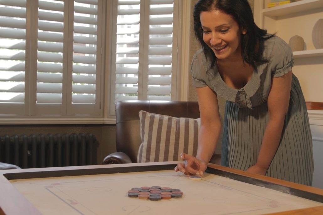 A player lining up a shot on a carrom board